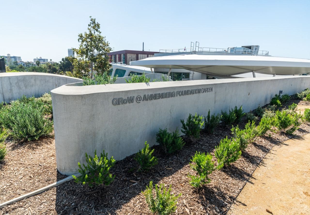 The GRoW @ Annenberg Foundation Garden, with planted beds along a curved concrete wall and the building beyond