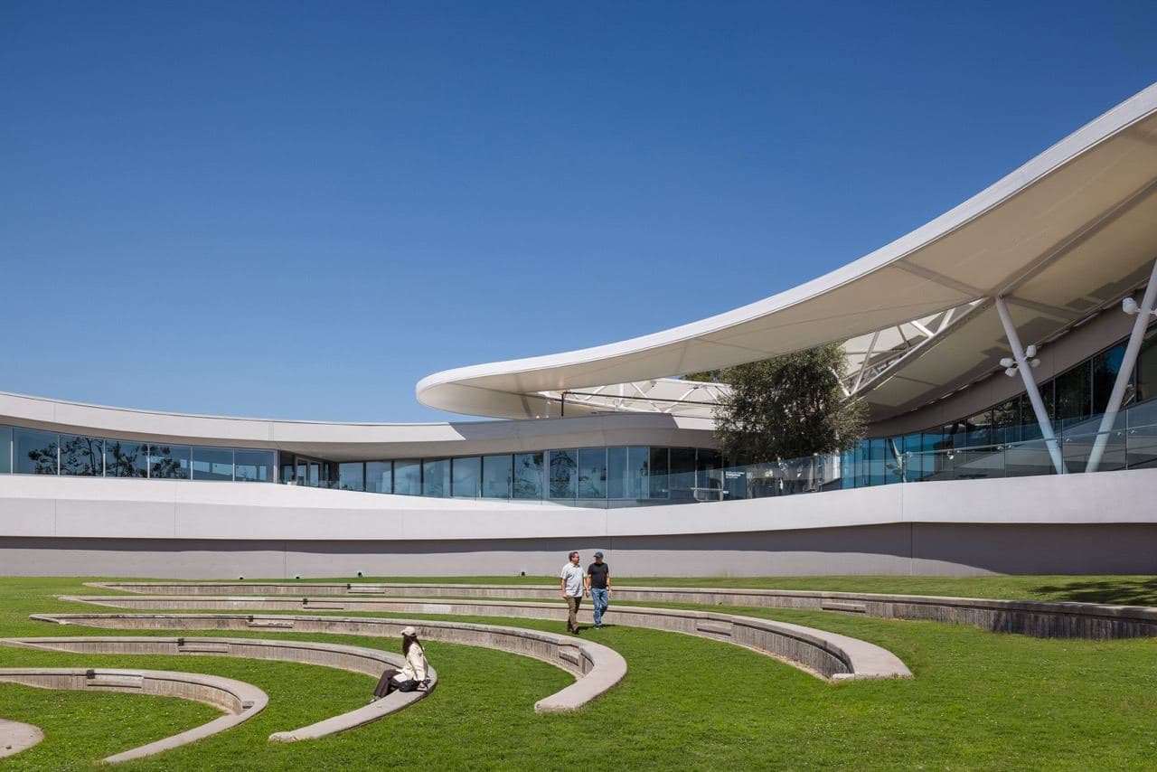 The outdoor amphitheater at The Goldrich on a clear day, with visitors on the lawn and the building's white canopy above