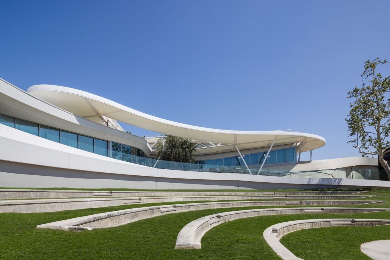 The Goldrich Cultural Center's white canopy roof and glass facade above the curved lawn amphitheater on a clear day