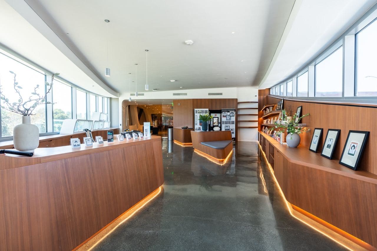 The Museum Shop: walnut counters and shelves with books, framed photographs and objects, lit by floor-to-ceiling windows