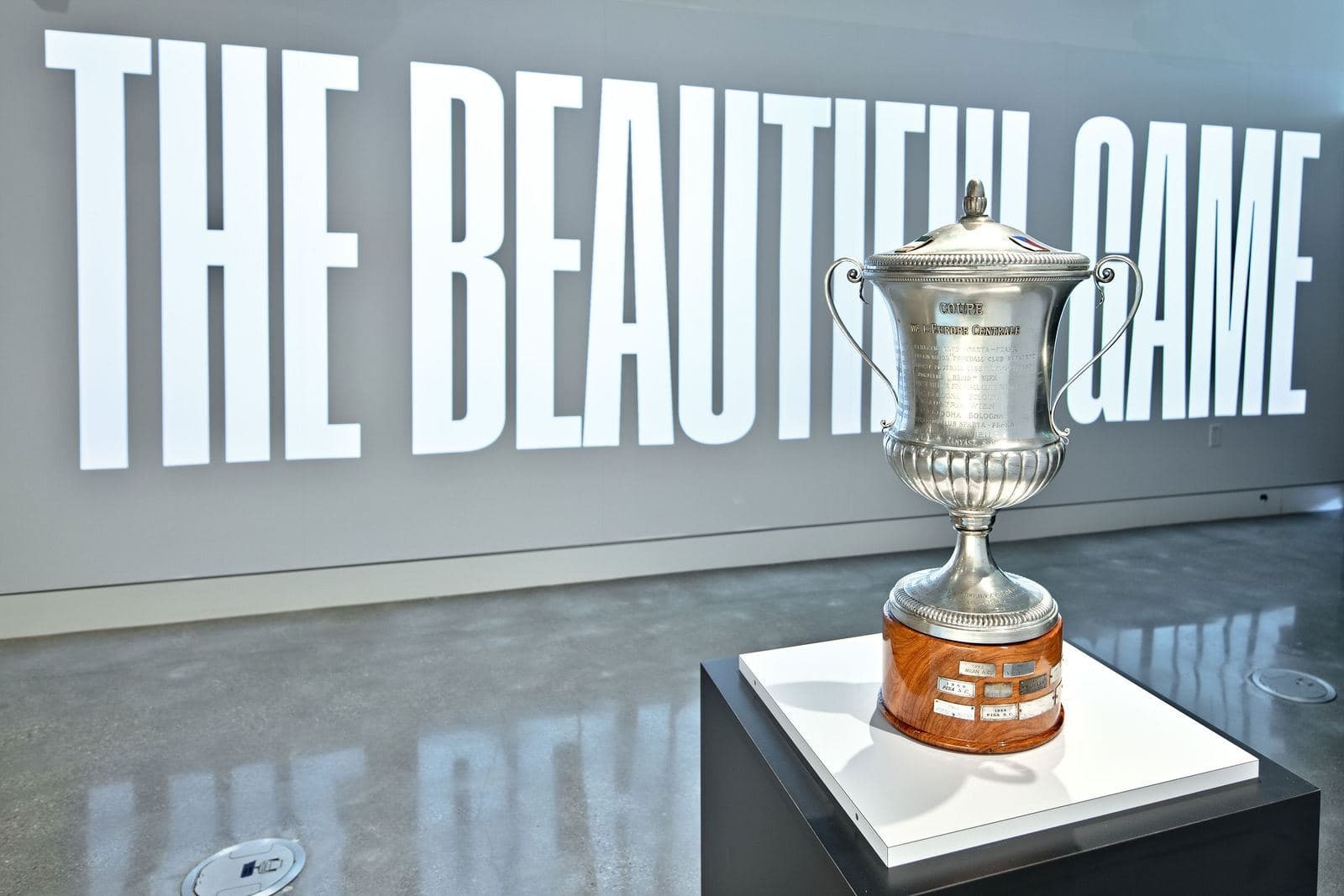 The Beautiful Game exhibition: the Mitropa Cup trophy on a plinth in front of the illuminated title wall
