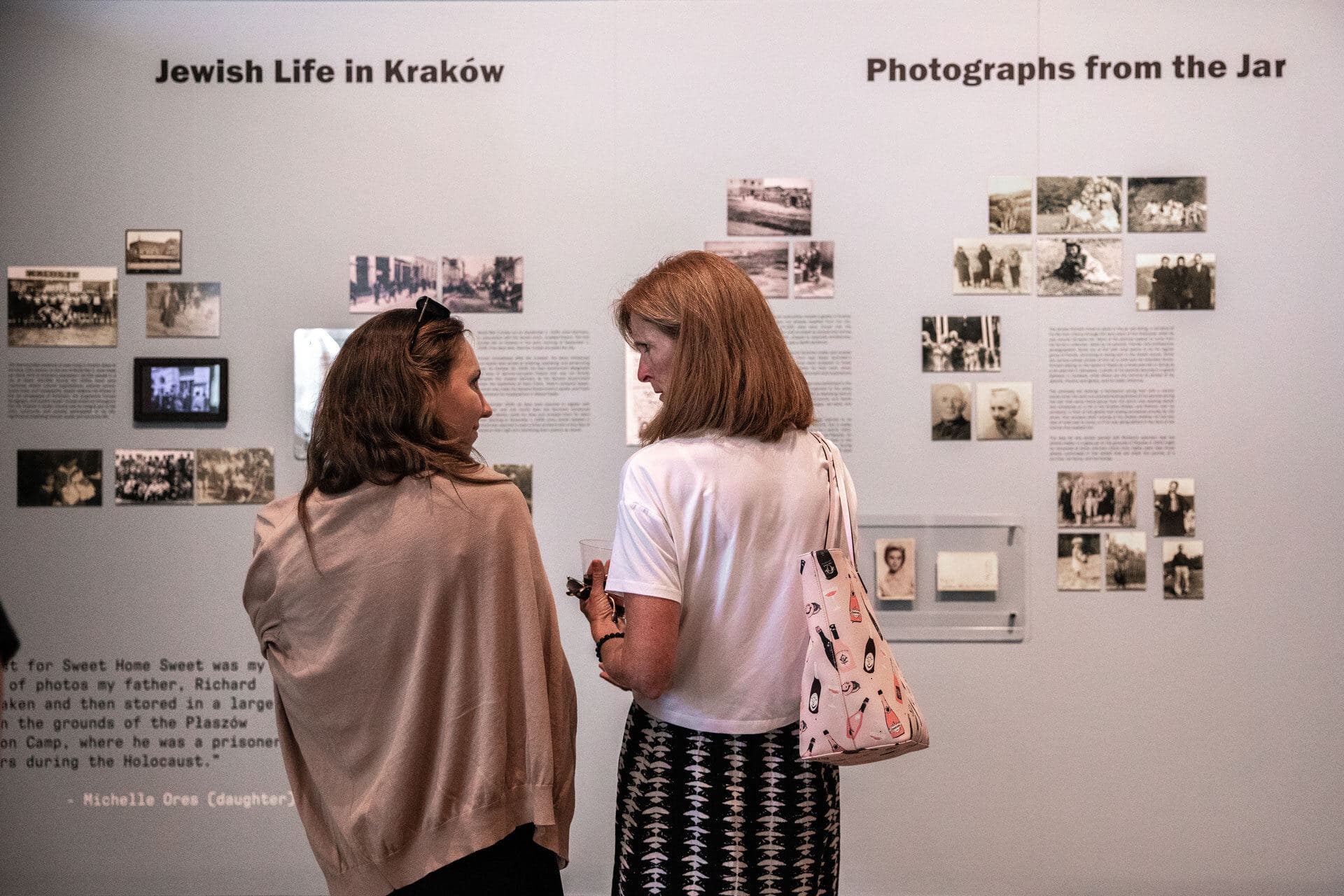 Two visitors looking at a wall of family photographs in the Jewish Life in Kraków gallery