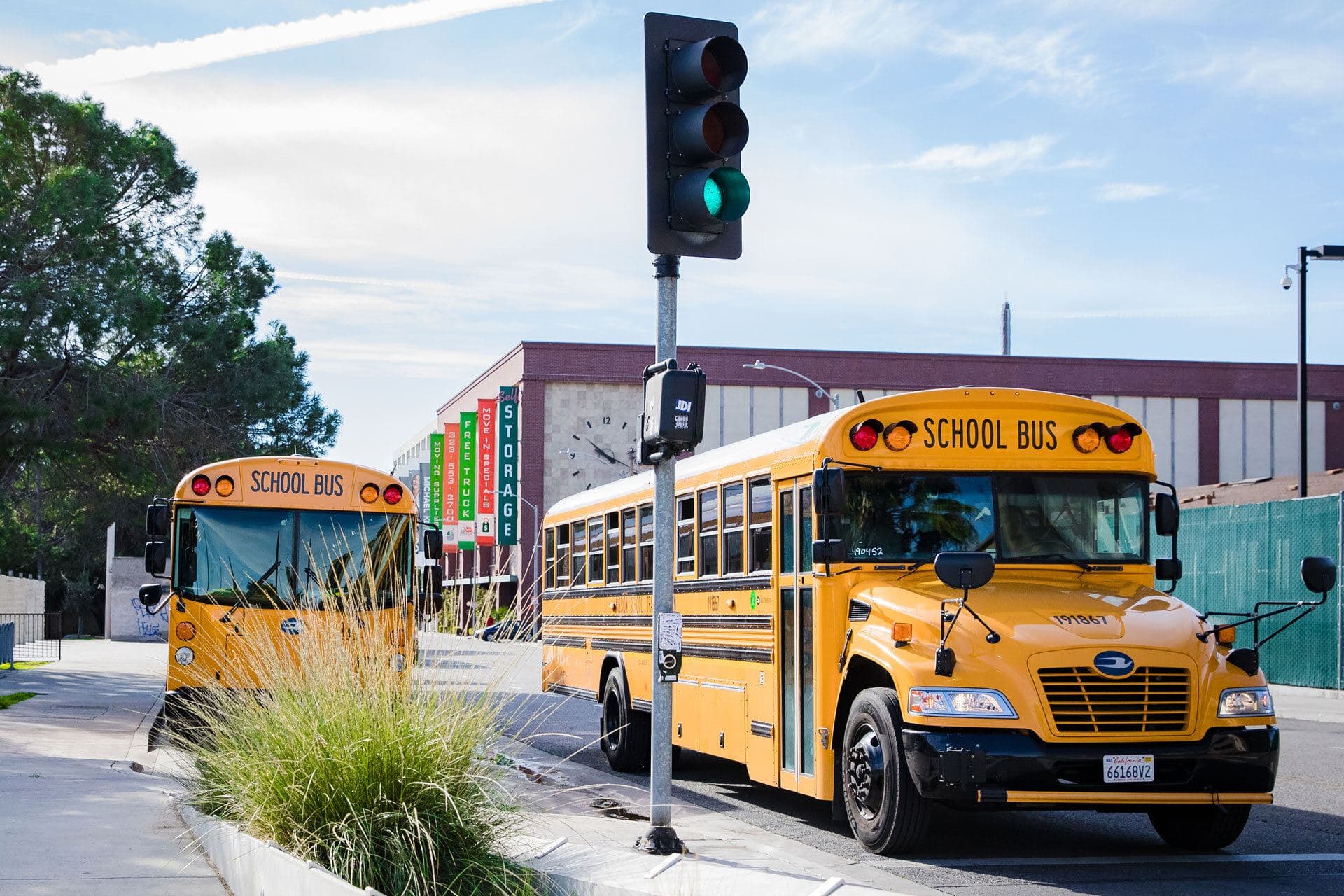 Two yellow school buses pulling up to the curb outside the Museum