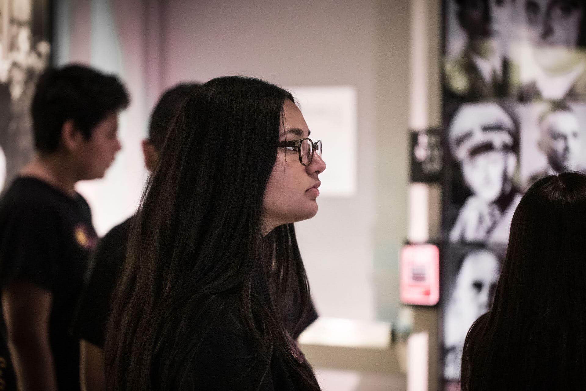 Students on a docent-led tour, looking at a wall of portraits in the permanent exhibition