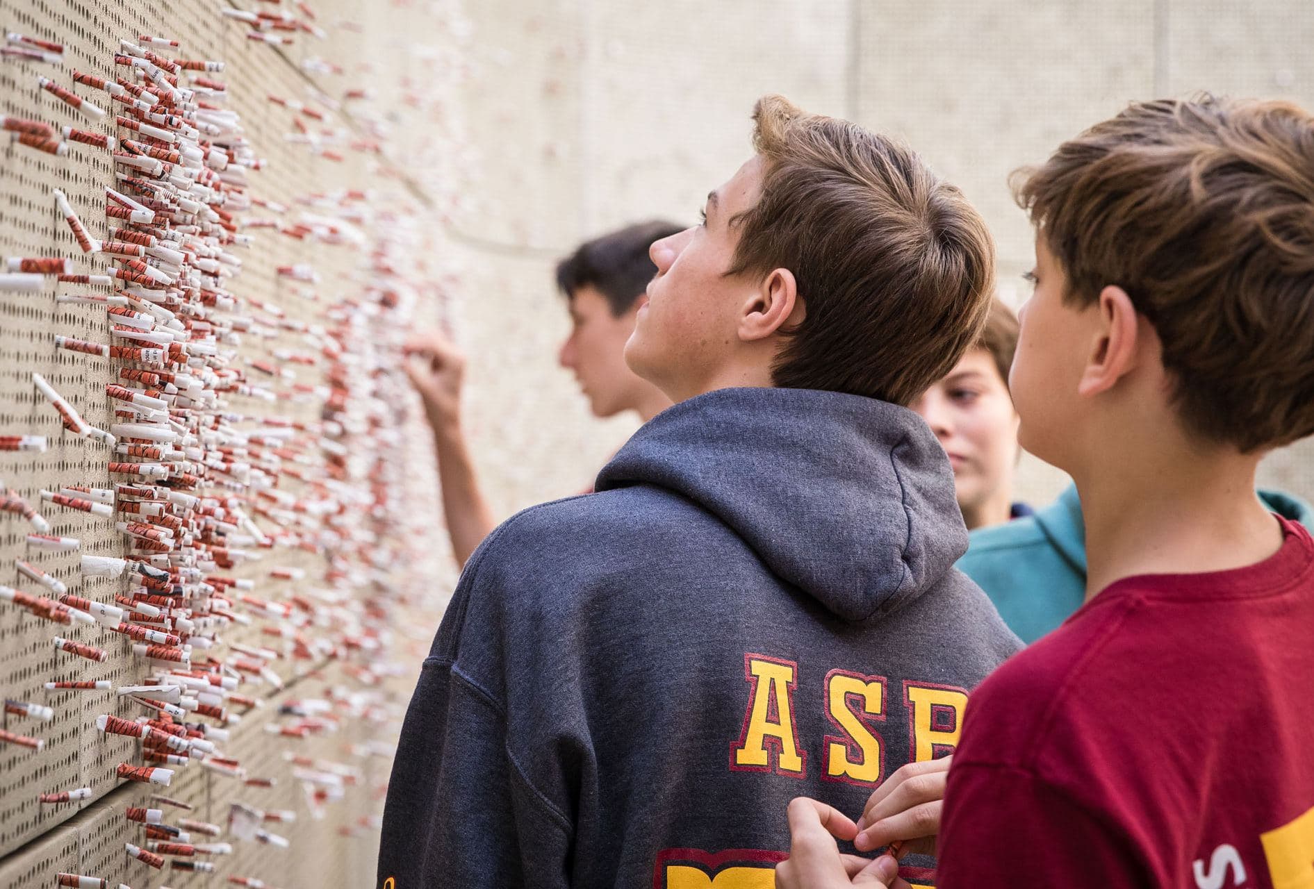 Students reading rolled messages placed in the Tree of Testimony memorial wall